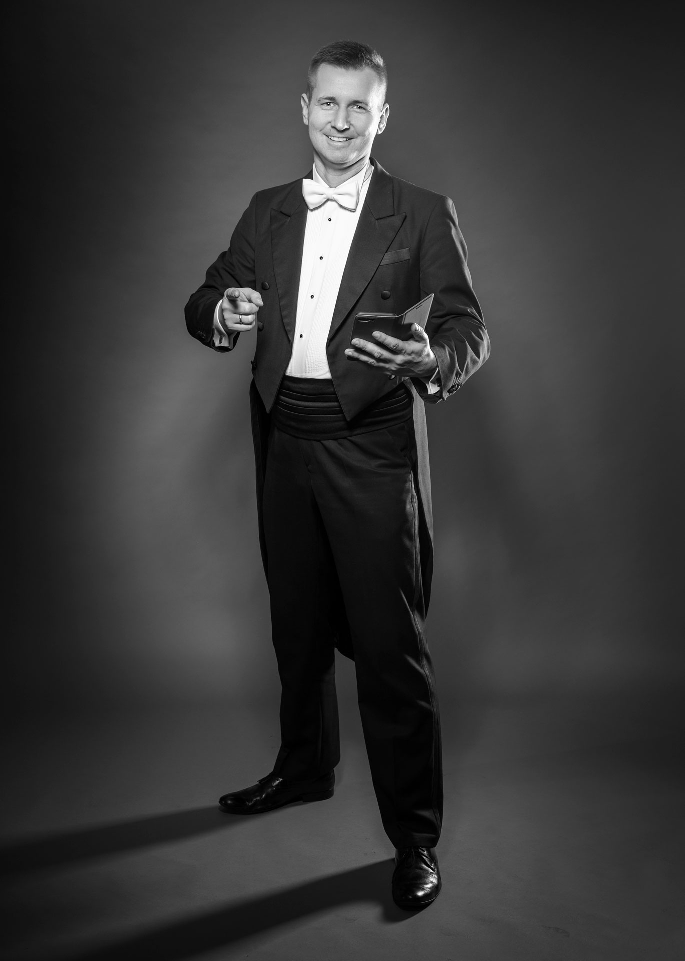 Wodzirej Karpik we fraku i z telefonem, który służy zwykle do szybkiego odpisywania na emaile