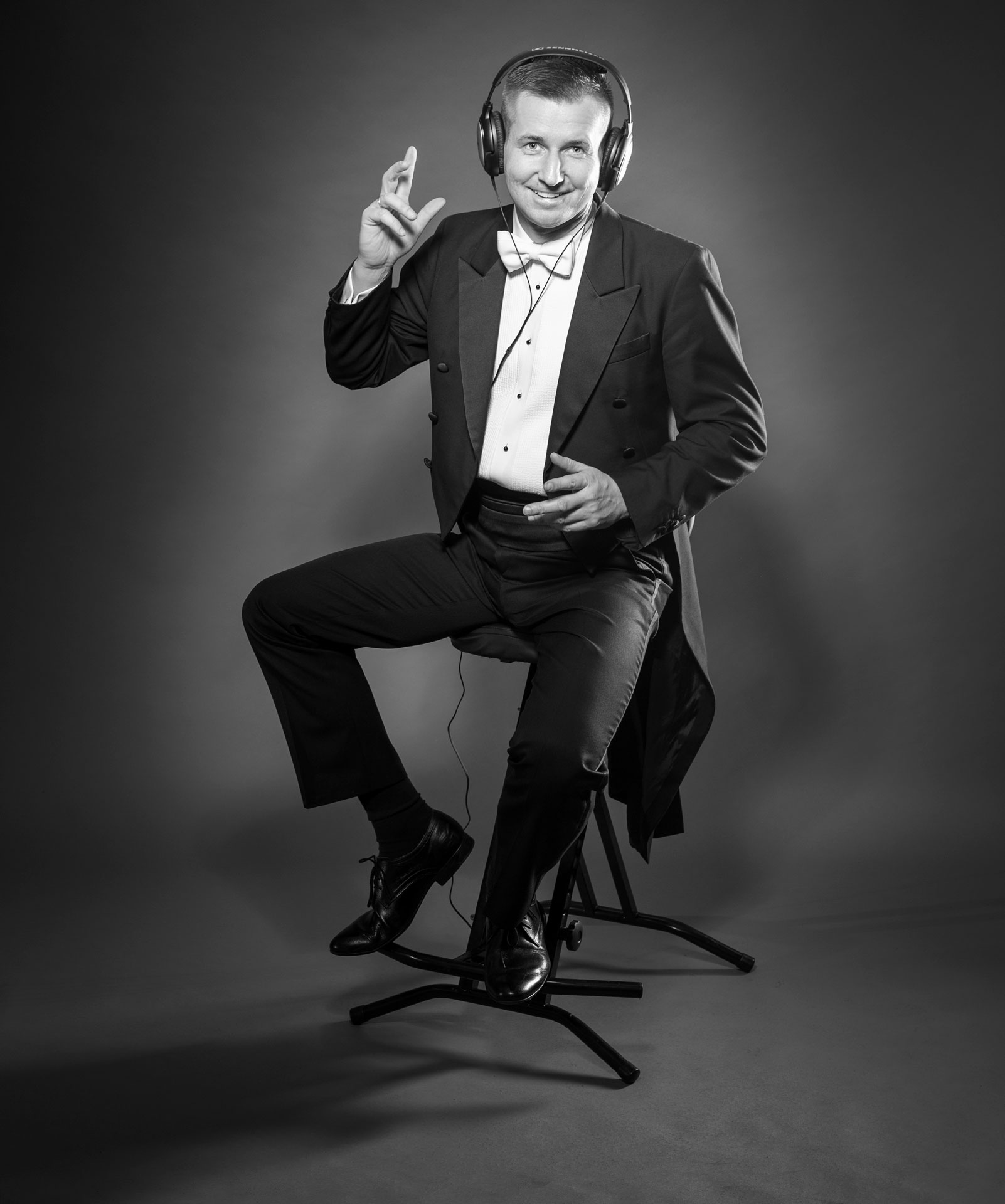 Wodzirej Karpik we fraku i z założonymi słuchawkami do odsłuchiwania muzyki przed jej zagraniem