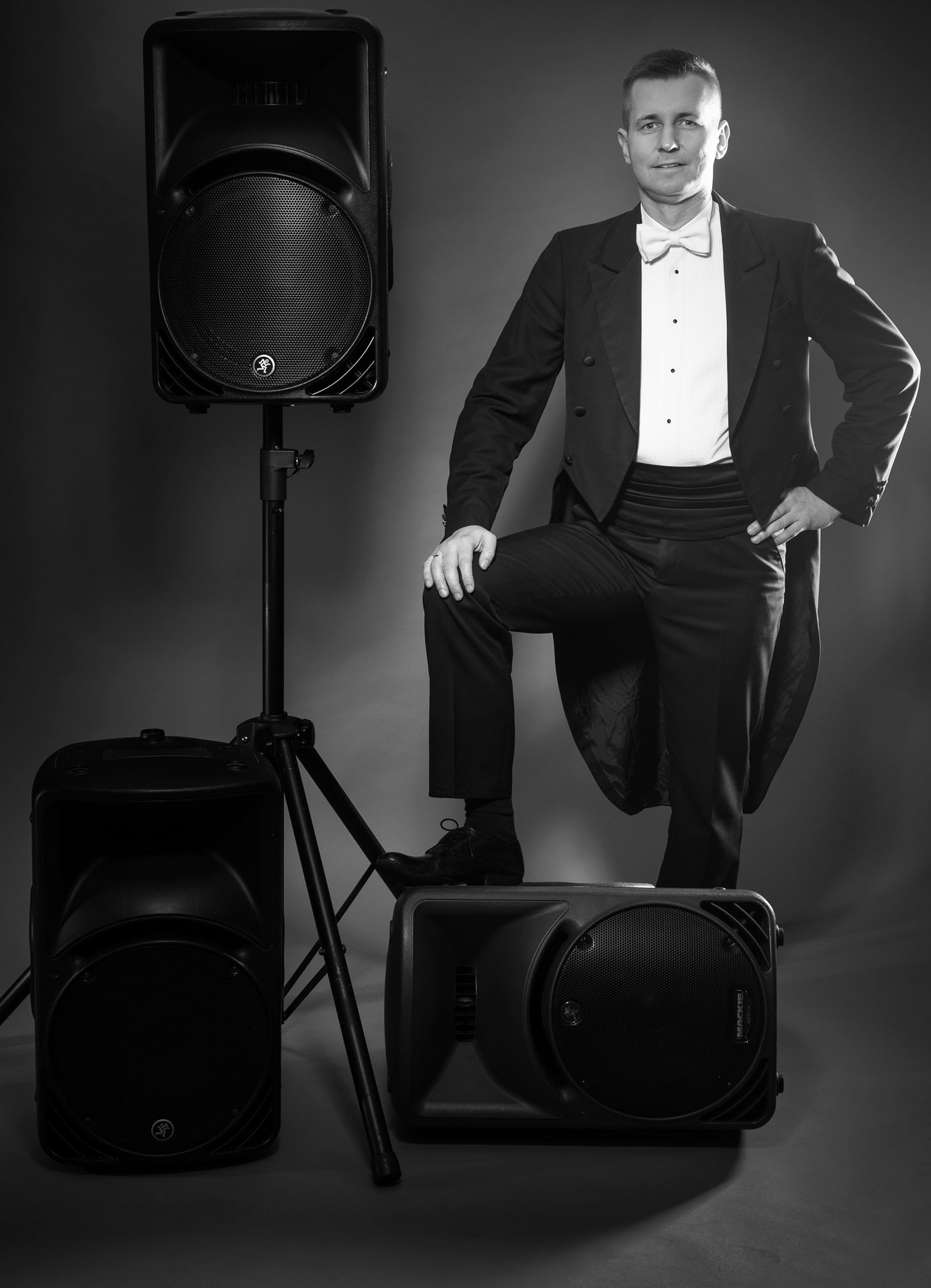 Wodzirej Karpik we fraku z głośnikami służącymi jako dodatkowe odsłuchy na salach weselnych