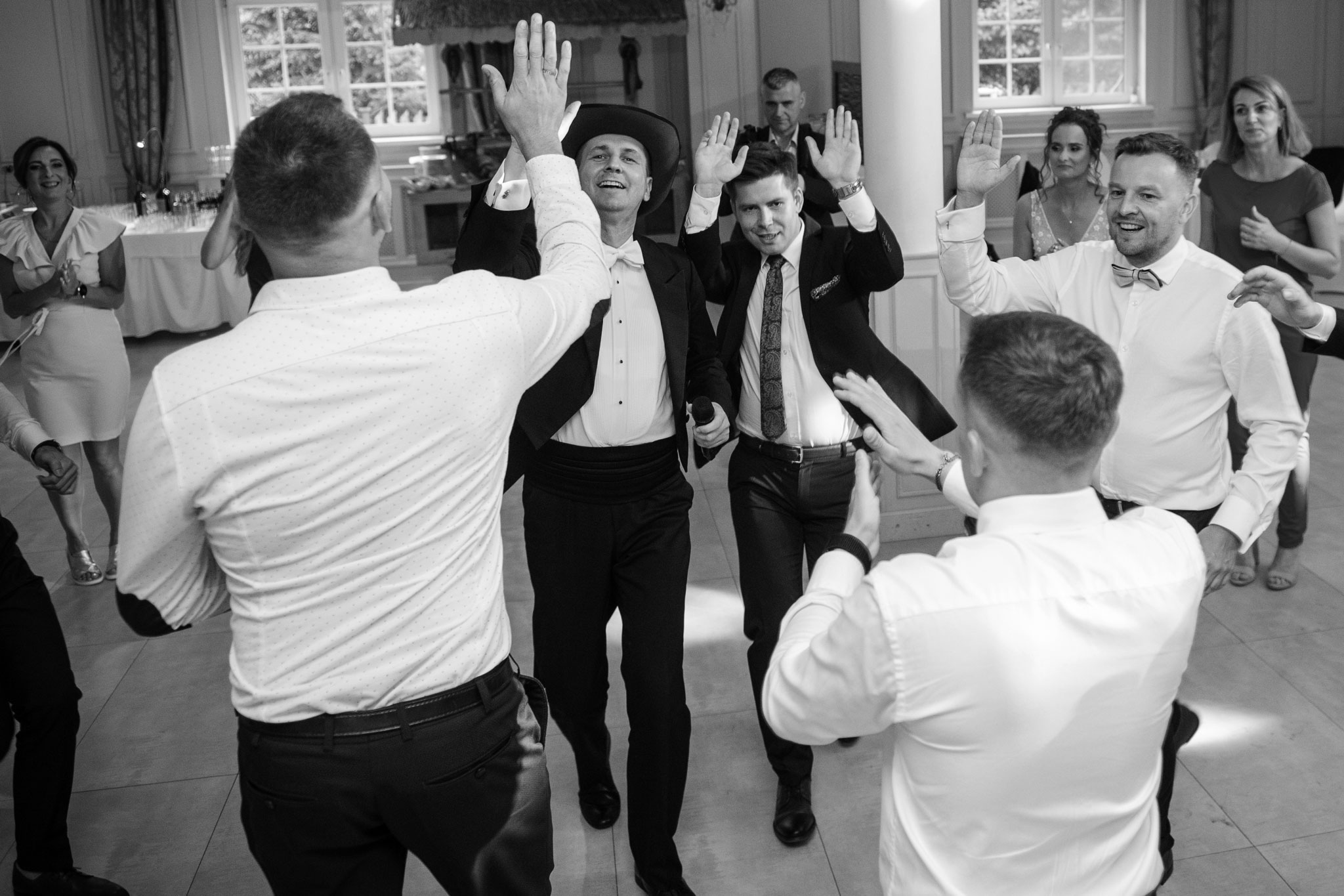 Wodzirej Karpik w kowbojskim kapeluszu prowadzący taniec na weselu